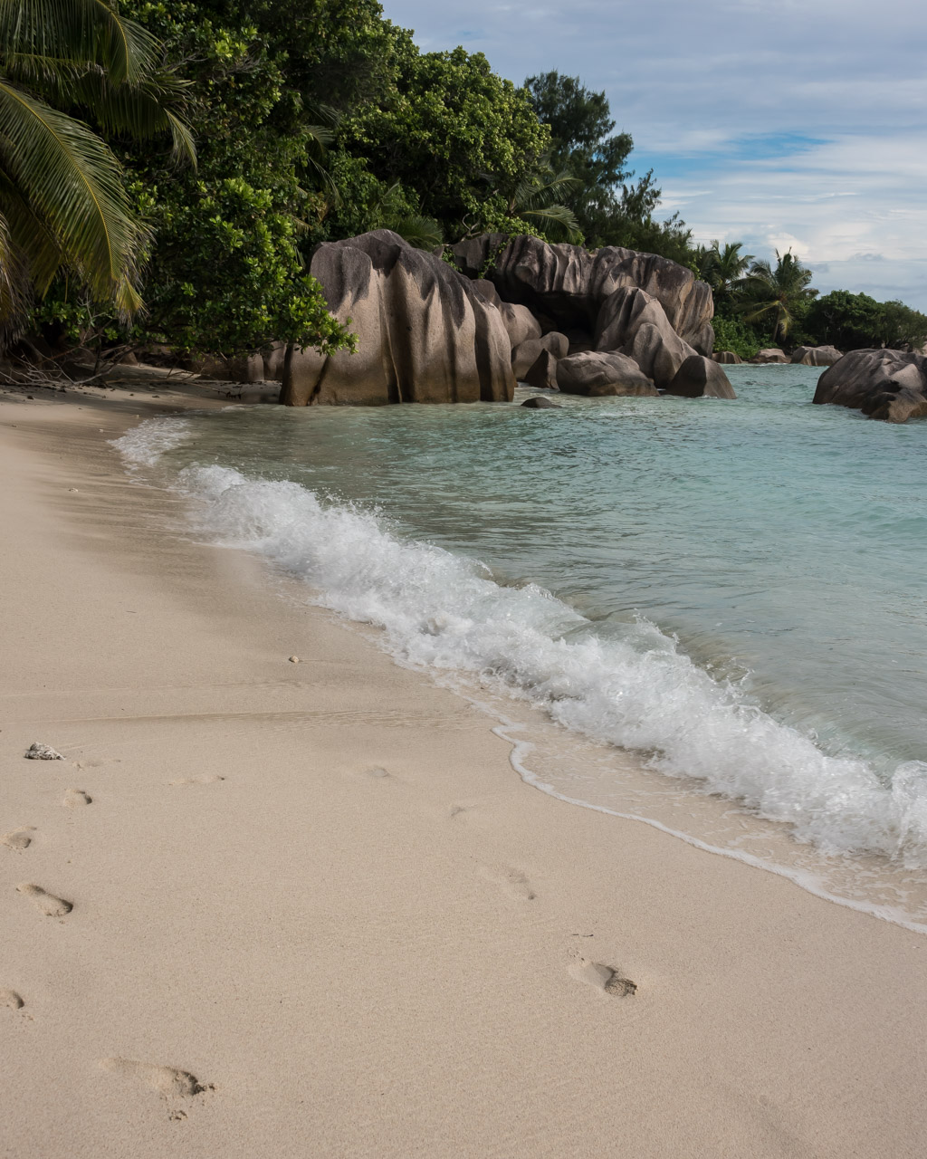 Klipper i havet på stranden La Digue Anse Pierrot i Seychellerna