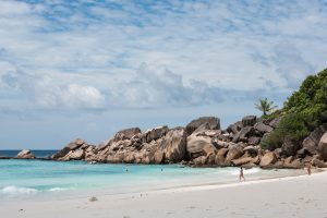 Sandstrand med turkisblåt vand og klipper på Seychellerne